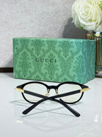 Black eyeglasses with gold-accent temples and clear lenses, side angle.