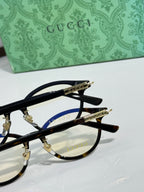 Black eyeglasses close-up showing gold hinge and logo on the temples.