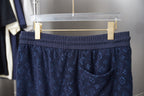 Navy patterned drawstring shorts on hanger, elastic waistband visible