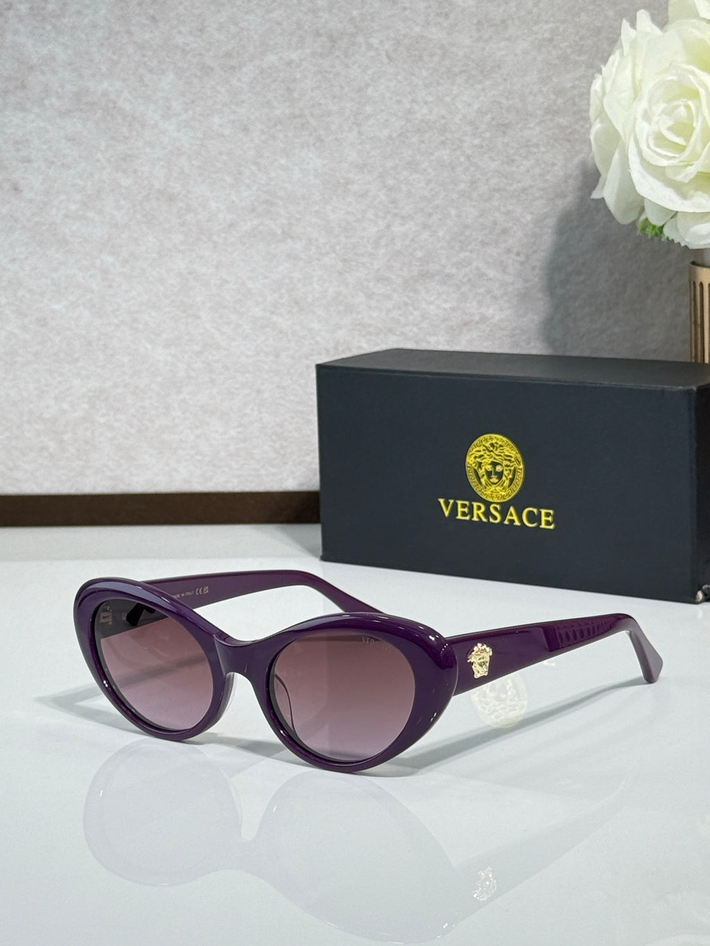 Versace purple sunglasses with pink lenses and gold logo on temple