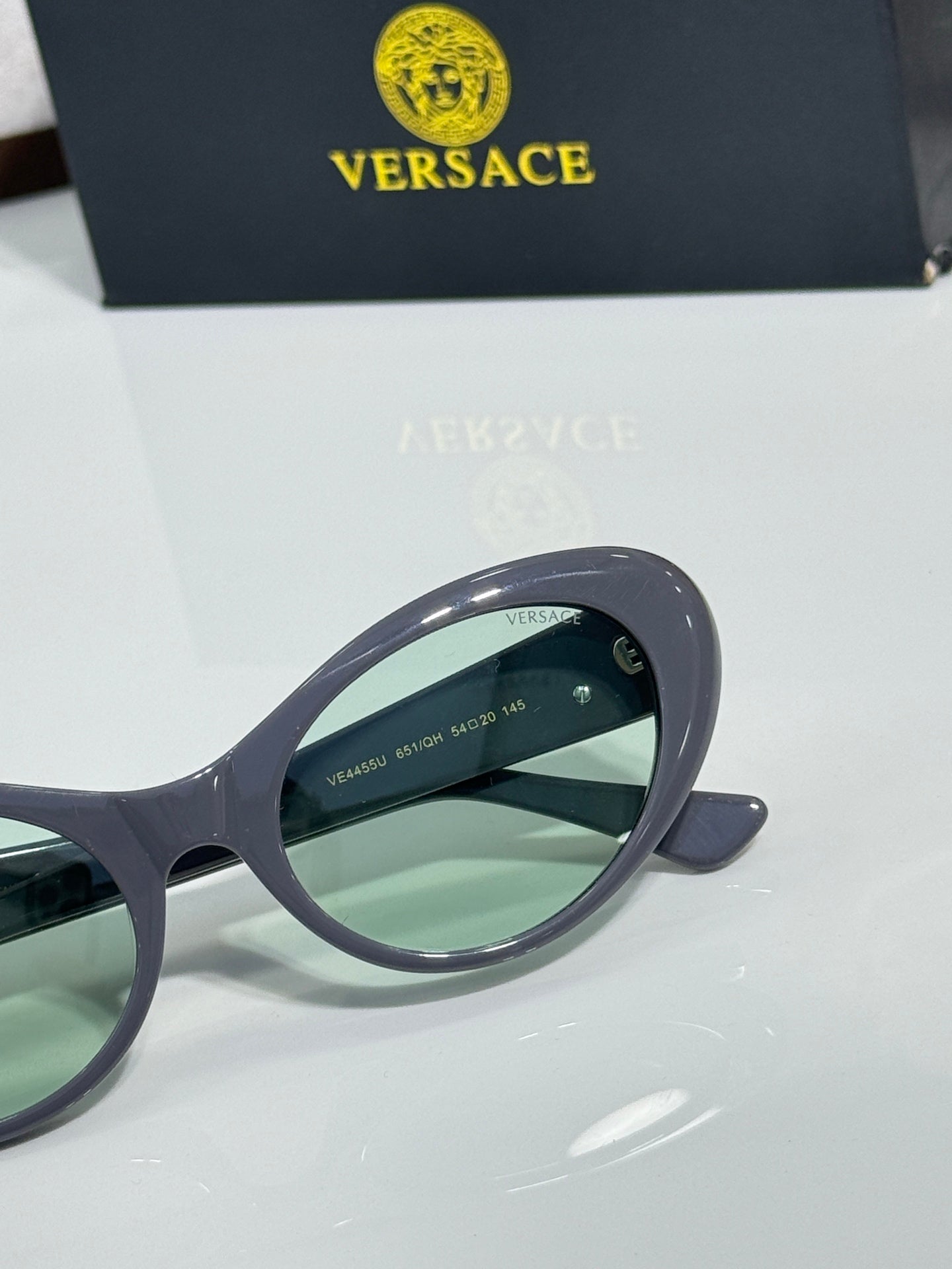 Versace dark sunglasses close-up with green lenses and curved frame