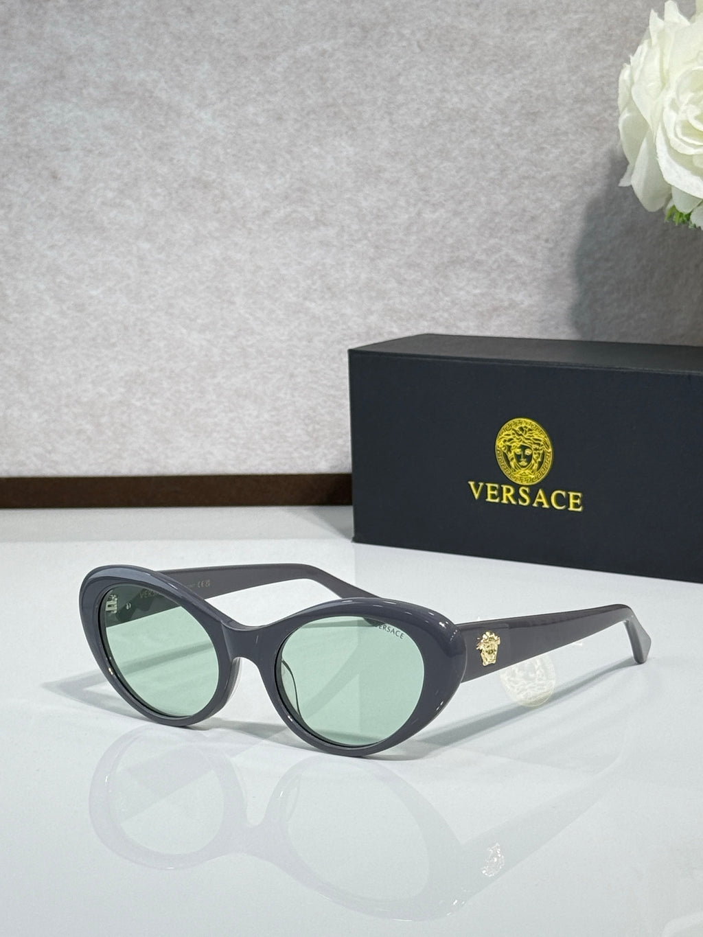 Versace black sunglasses with green-tinted lenses and clear temple tips