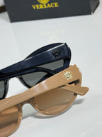 Versace beige sunglasses close-up with gold logo on side and dark lens