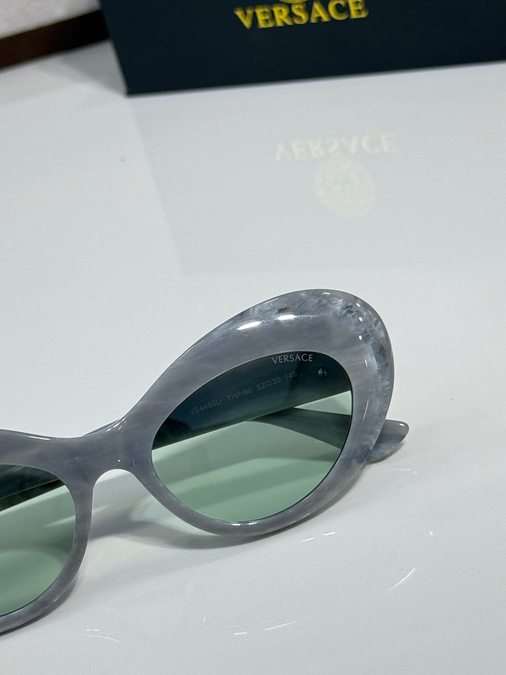 Versace sunglasses with clear gray frames and mint green lenses close-up