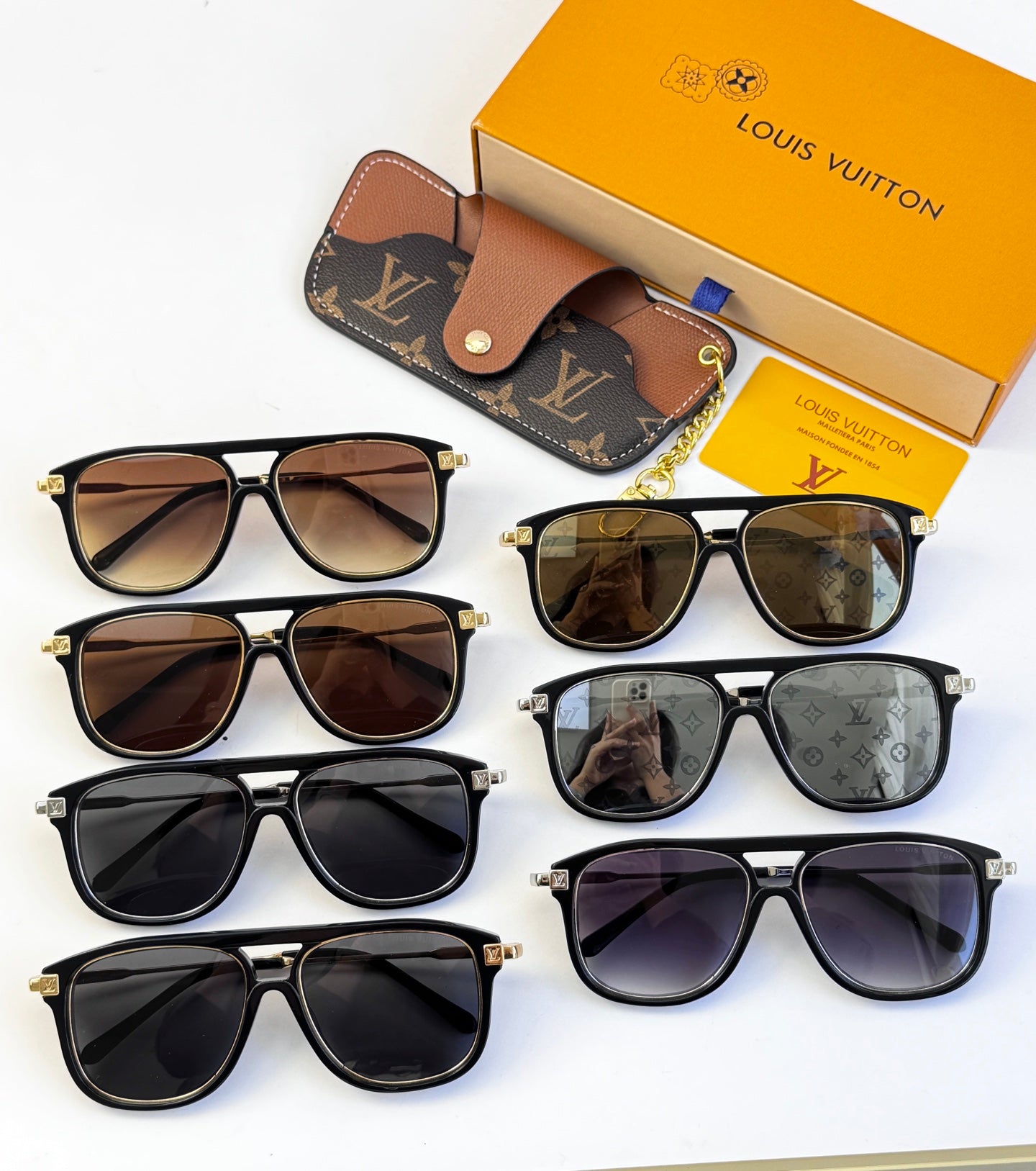Collection of sunglasses with tinted lenses and black frames, with LV pouch and box