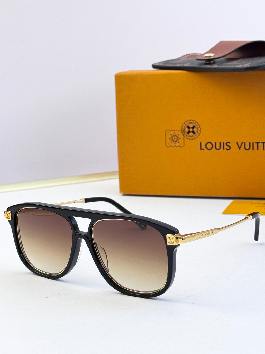 Sunglasses with black frames and gradient brown lenses, gold-tone metal accents
