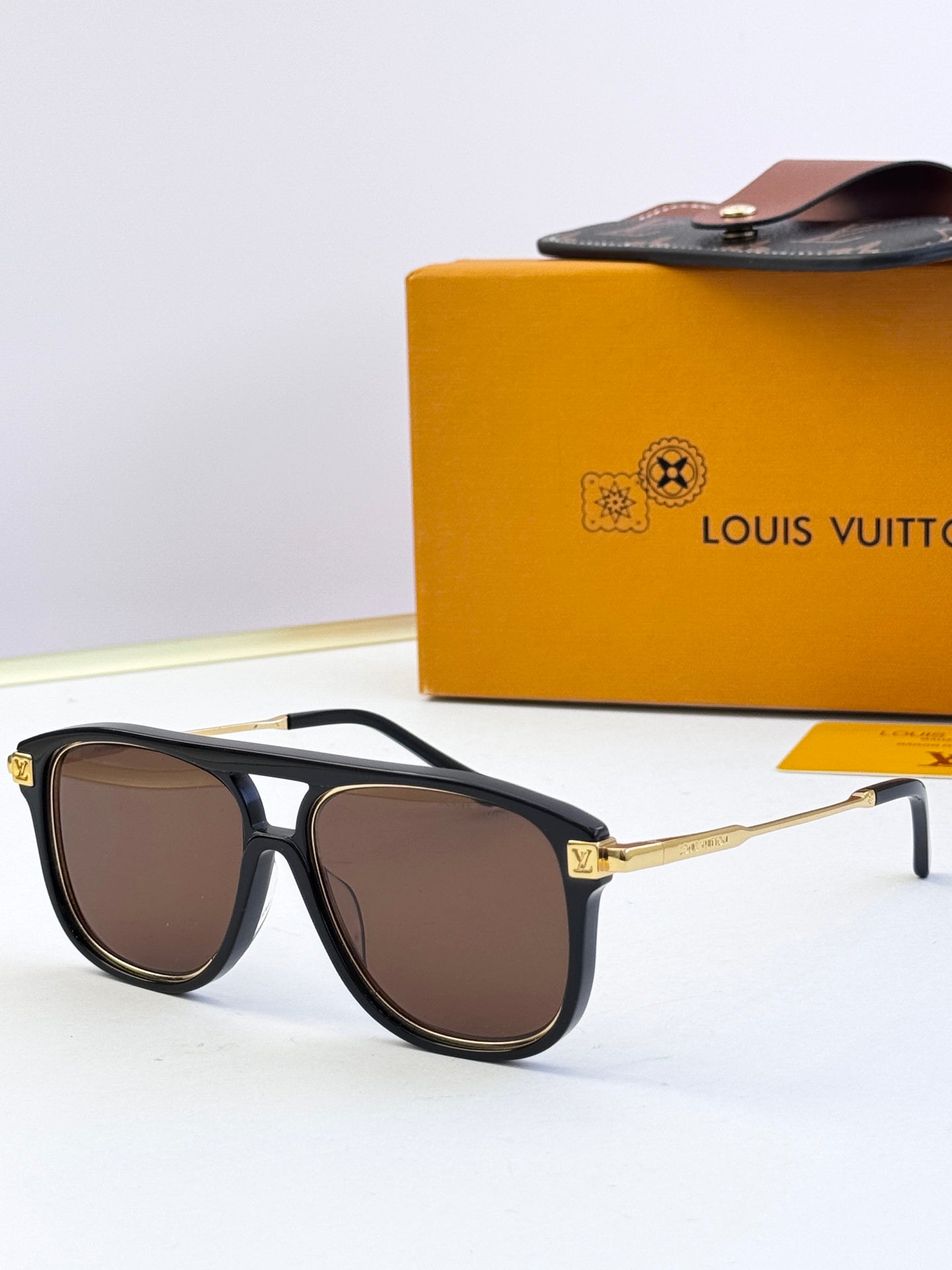 Sunglasses with black frames and brown-tinted lenses, gold-tone logo detail