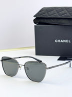 Chanel sunglasses with dark gray lenses, silver-tone metal frames, rounded cat-eye shape