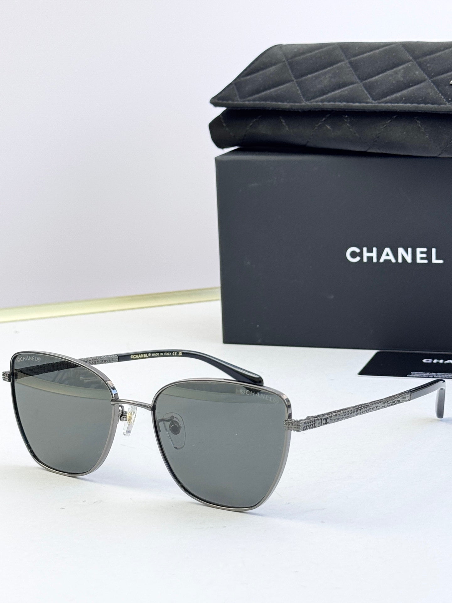 Chanel sunglasses with dark gray lenses, silver-tone metal frames, rounded cat-eye shape