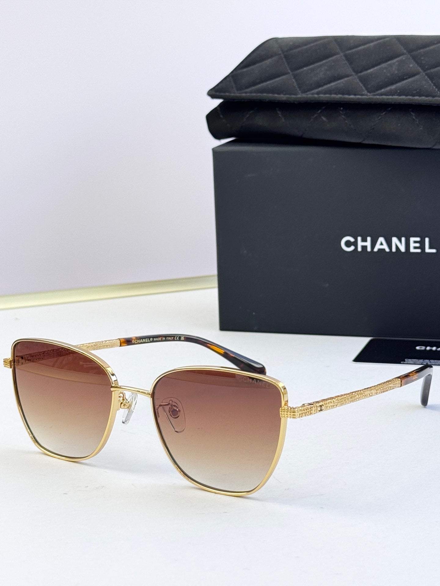 Chanel sunglasses with amber-brown lenses, gold-tone metal frames, rounded cat-eye frames