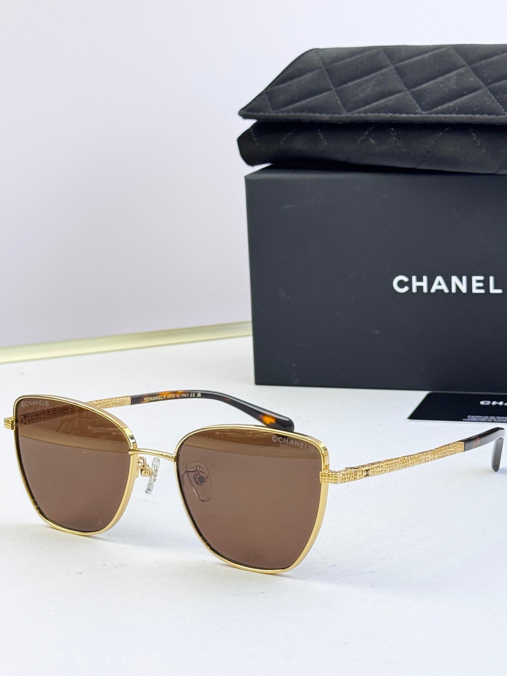 Chanel sunglasses with brown tinted lenses, gold-tone metal frames, rounded cat-eye style