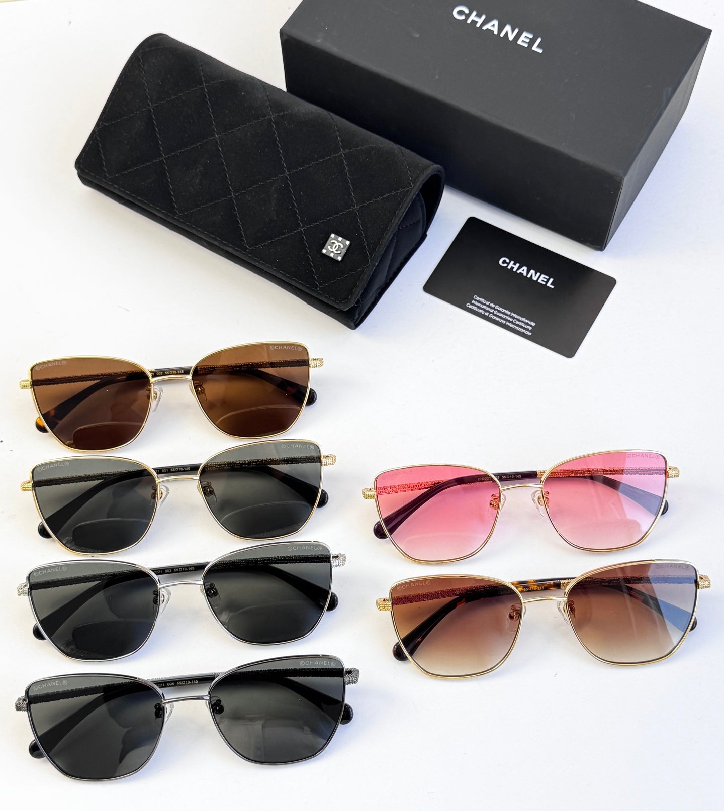 Assorted Chanel sunglasses on display: black, brown, and pink lenses with gold-tone frames