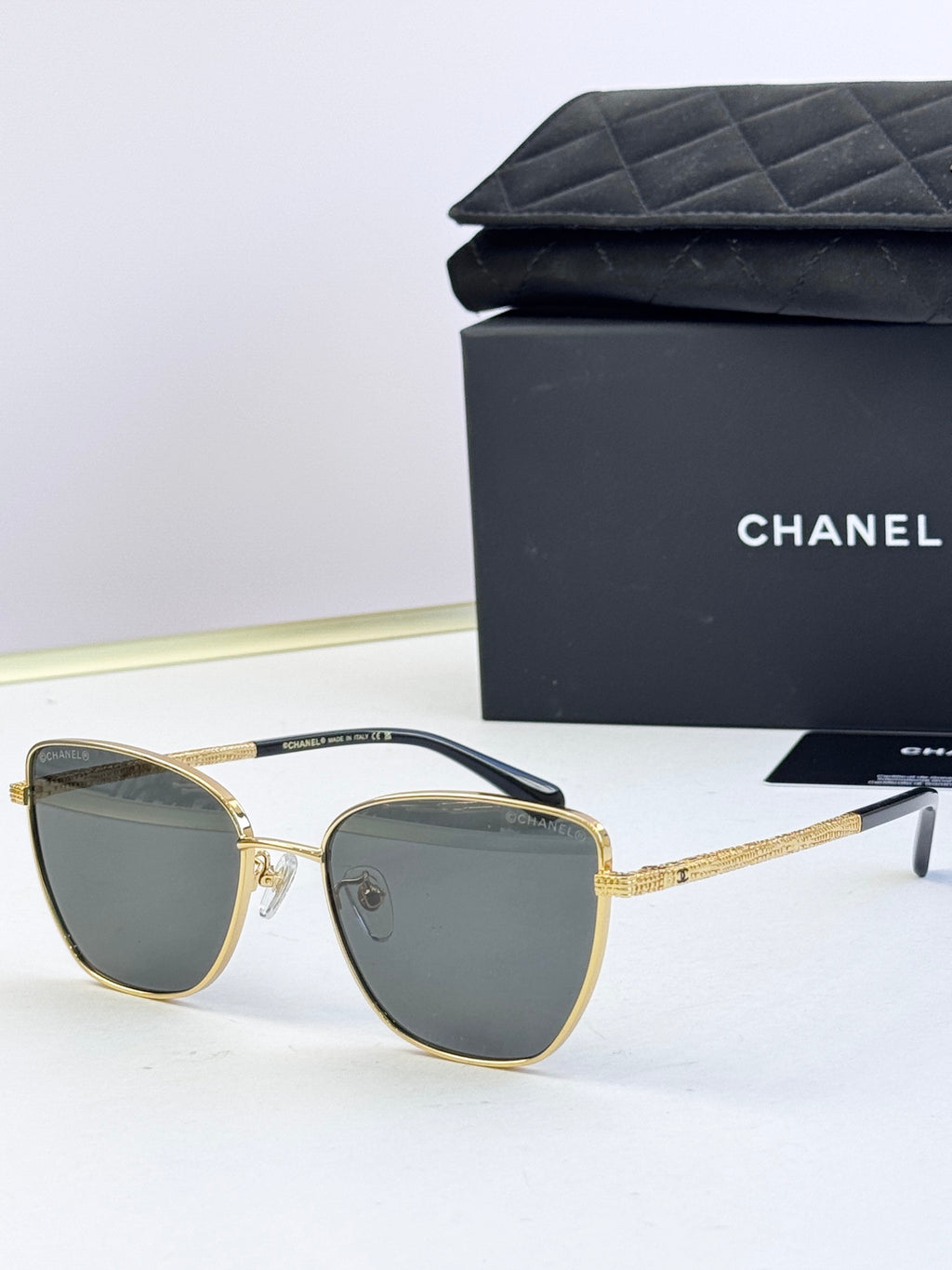 Chanel sunglasses with gray lenses, gold-tone metal frames, rounded cat-eye silhouette
