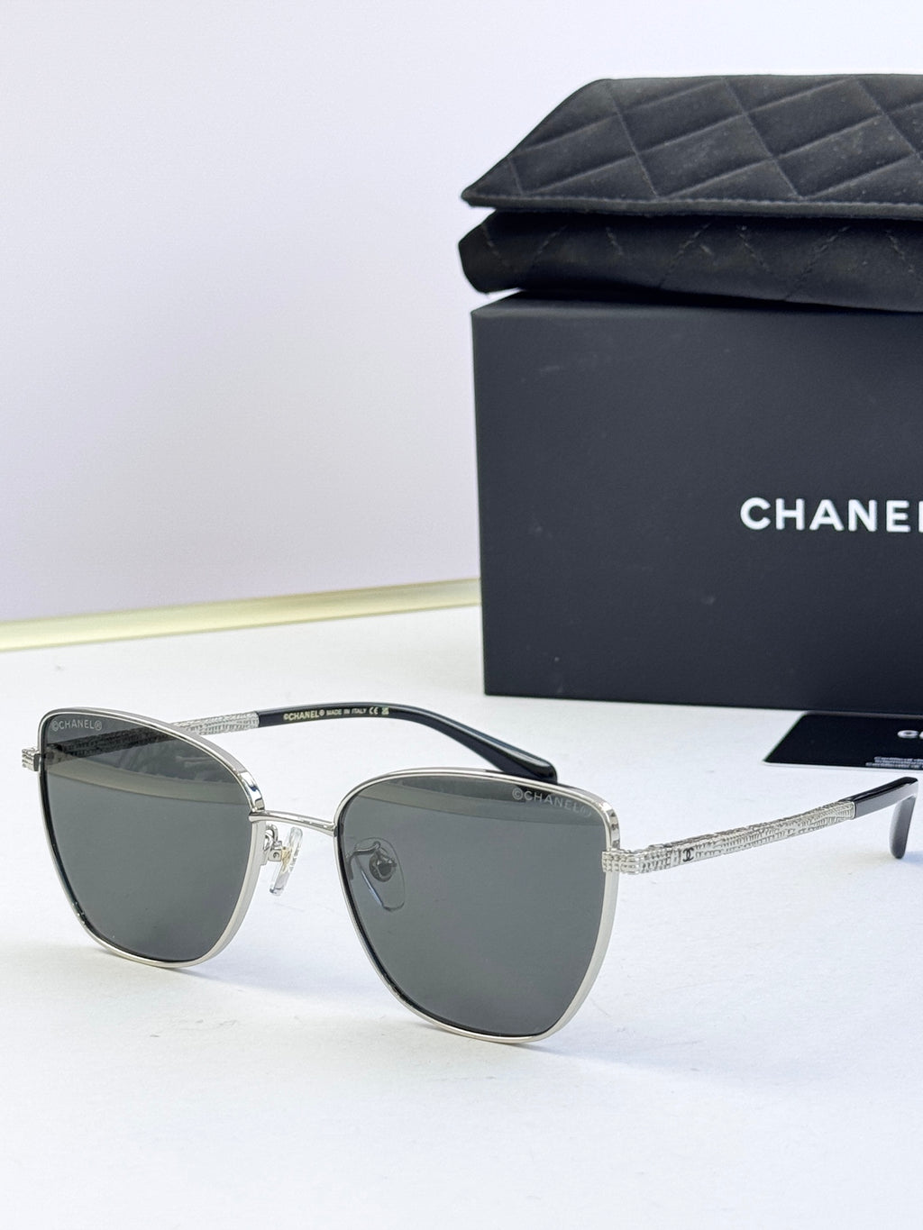 Chanel sunglasses with dark gray lenses, silver-tone metal frames, angled rounded shape