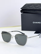 Chanel sunglasses with dark gray lenses, silver-tone metal frames, angled rounded shape