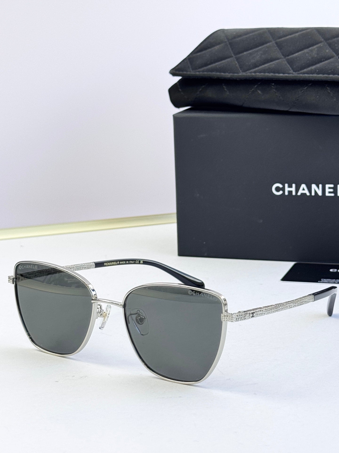 Chanel sunglasses with dark gray lenses, silver-tone metal frames, angled rounded shape