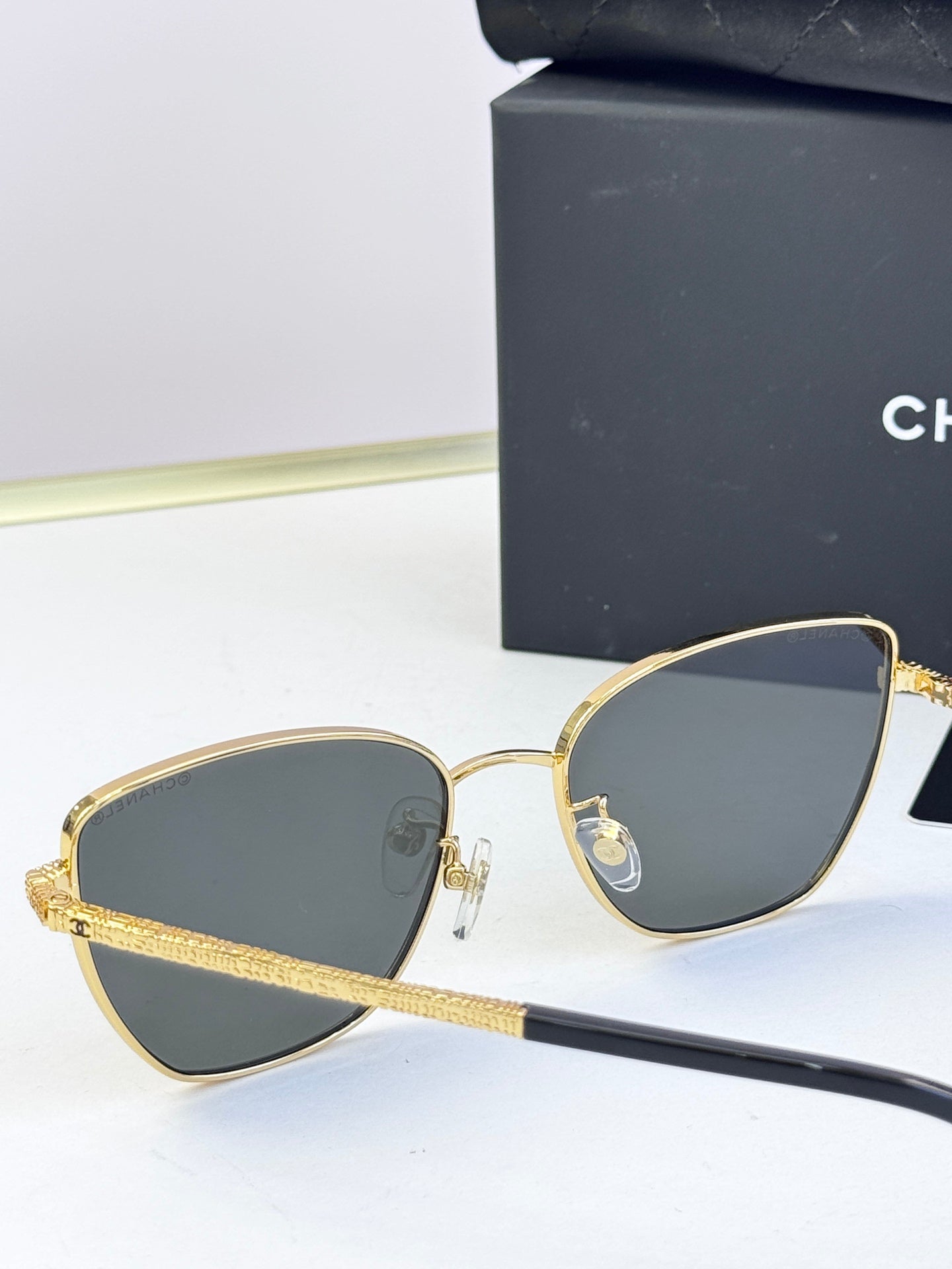 Chanel sunglasses pair, gold-tone metal frames with dark blue-gray lenses, rounded cat-eye