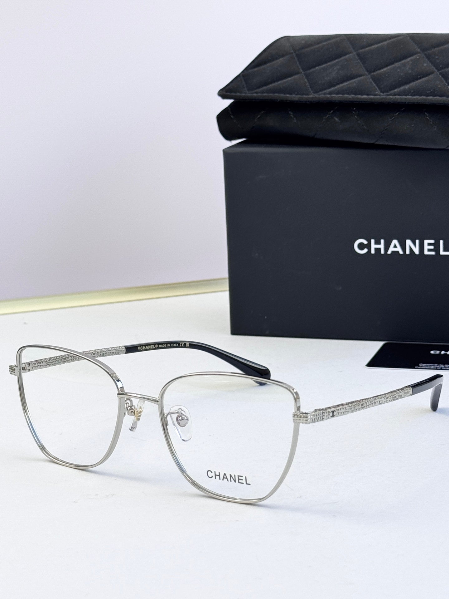 Silver metal eyeglasses with clear lenses, square frames, and dark temple tips