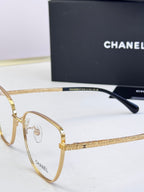 Gold eyeglasses close-up with textured arm and dark temple tip