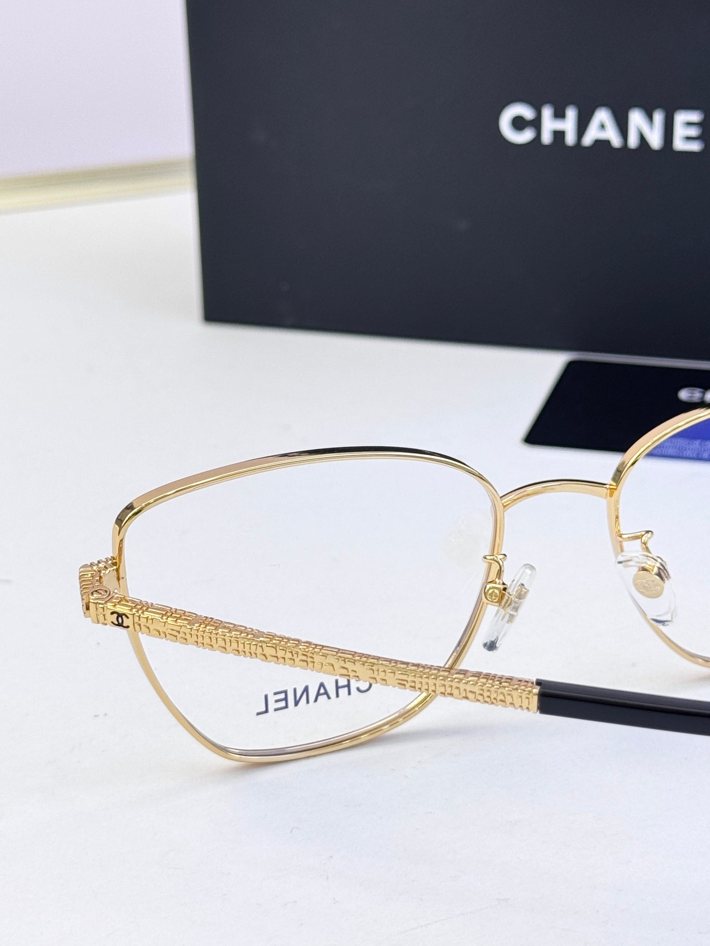 Gold metal eyeglasses with clear lenses and engraved temple branding