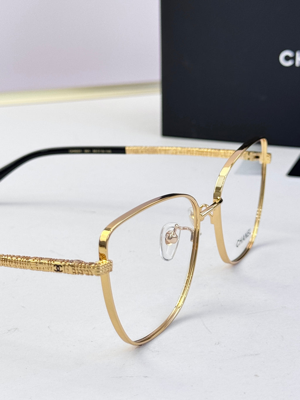 Gold eyeglasses close-up: hinge and temple with logo detailing