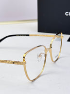 Gold eyeglasses close-up: hinge and temple with logo detailing