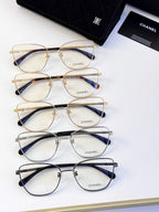 Set of four eyeglasses in gold, black, and silver tones with clear lenses