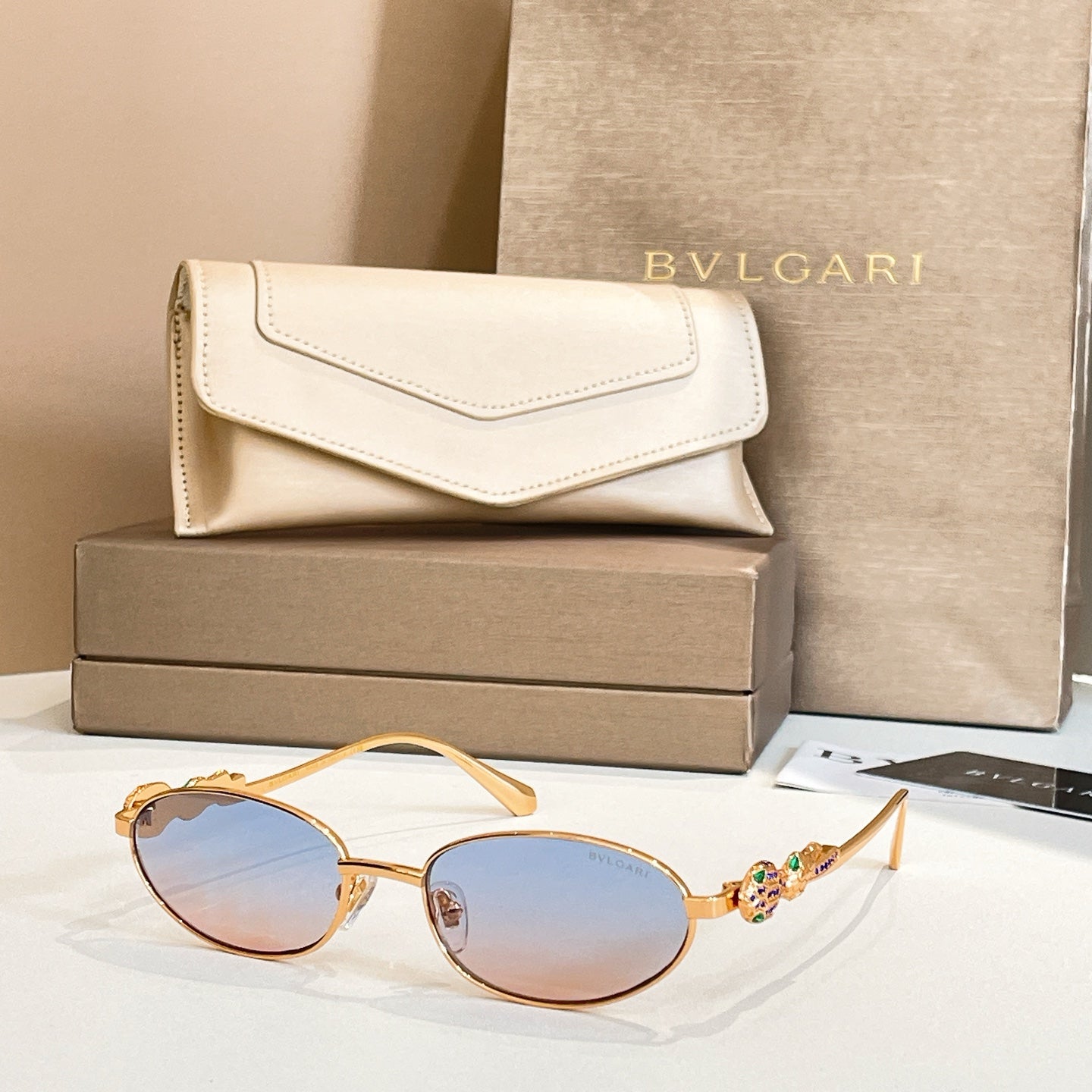 Bvlgari sunglasses with round light lenses and gold-tone frames, shown with case