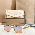 Gold-framed square sunglasses with light blue gradient lenses and jeweled temple detail