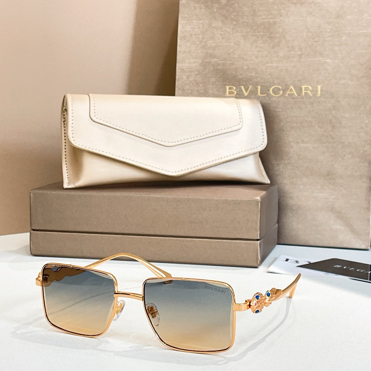 Gold-framed square sunglasses with blue gradient lenses and jeweled temple detail