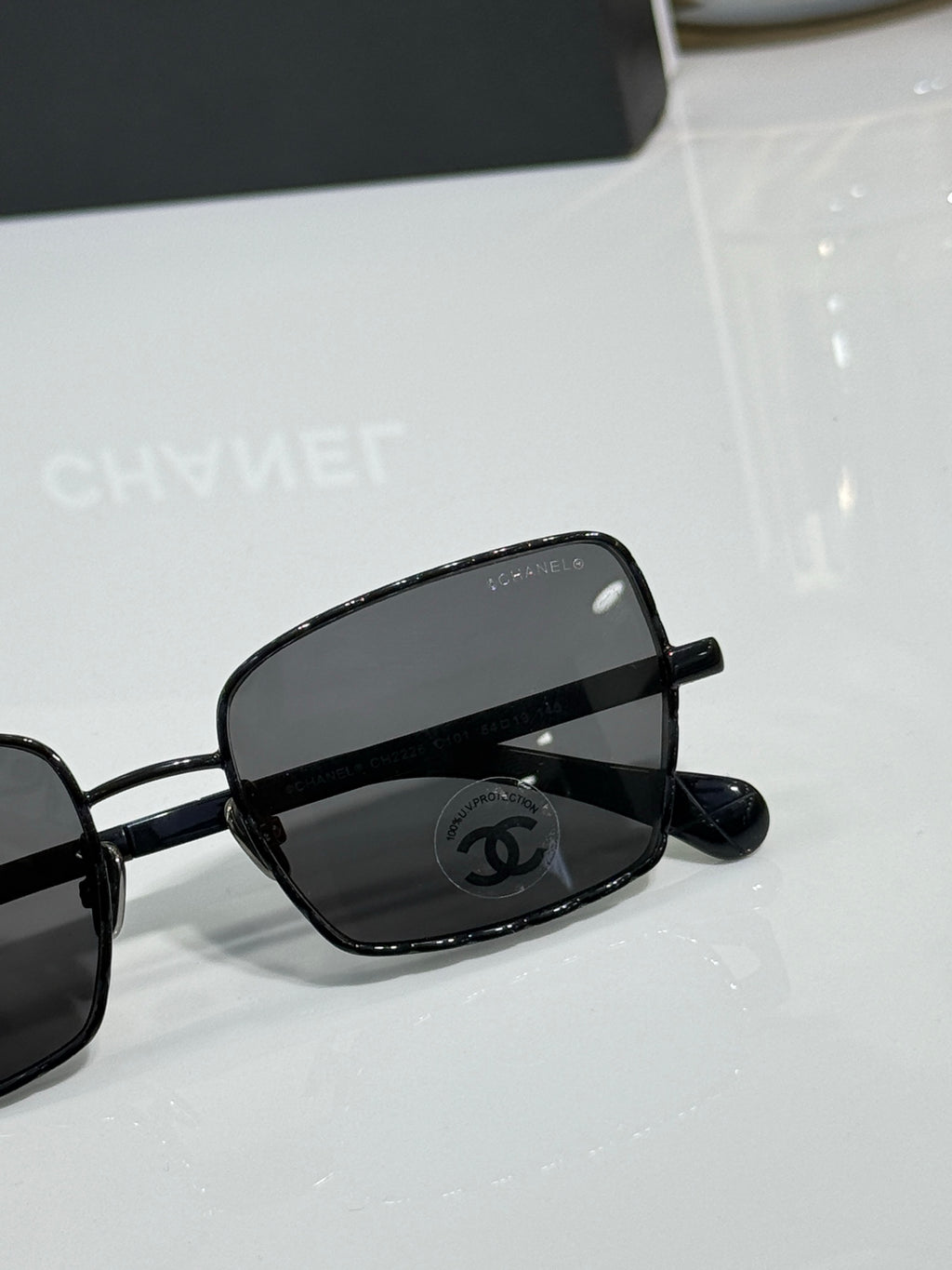 Black eyeglasses close-up with Chanel logo on lens