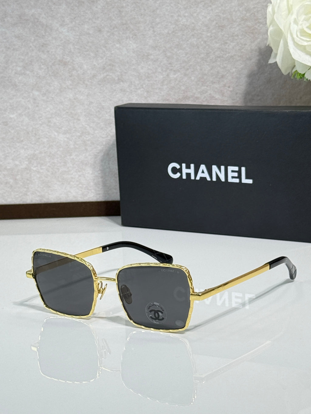 Square gold-tone eyeglasses with dark lenses, Chanel logo on temples