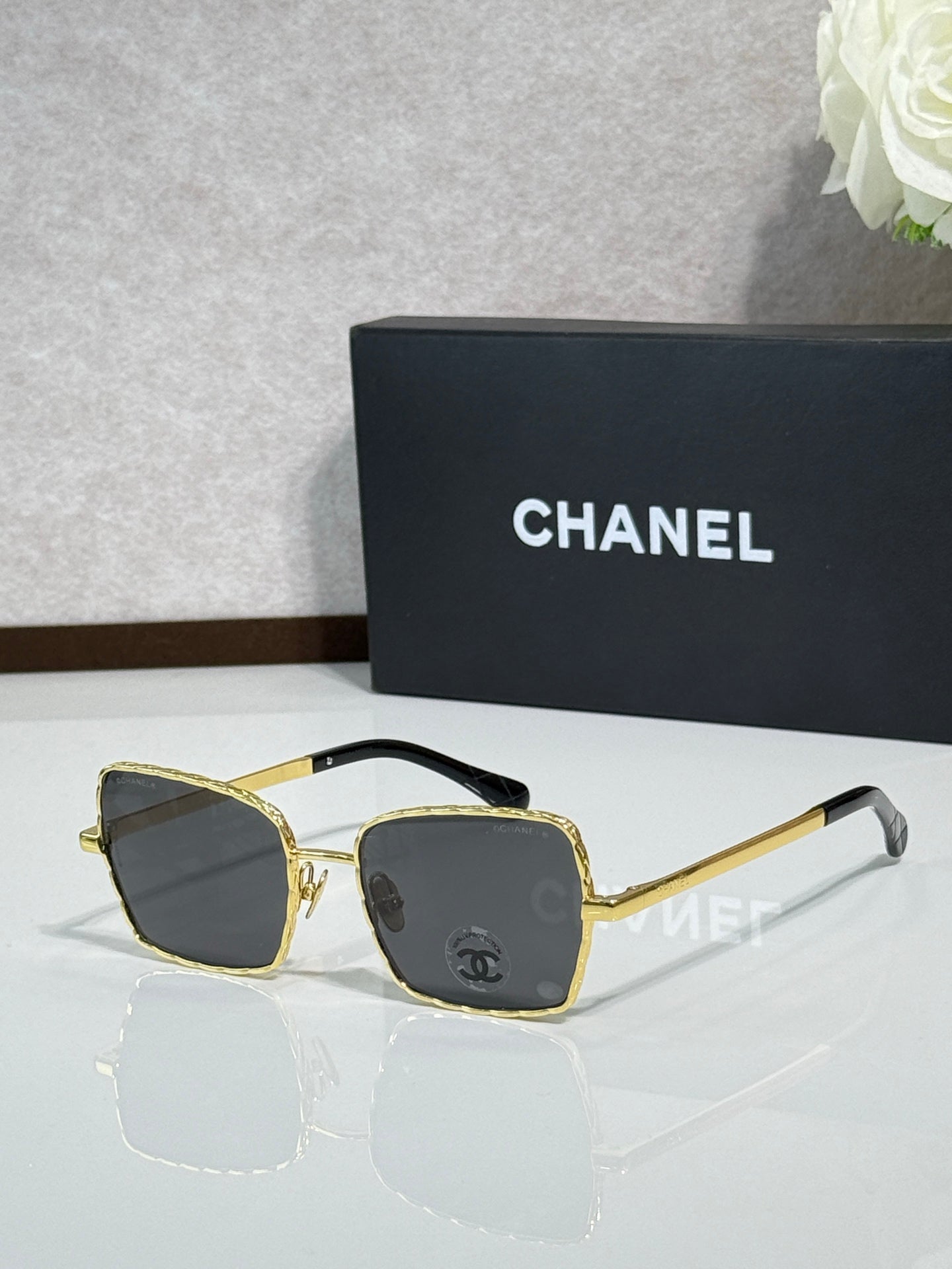 Square gold-tone eyeglasses with dark lenses, Chanel logo on temples