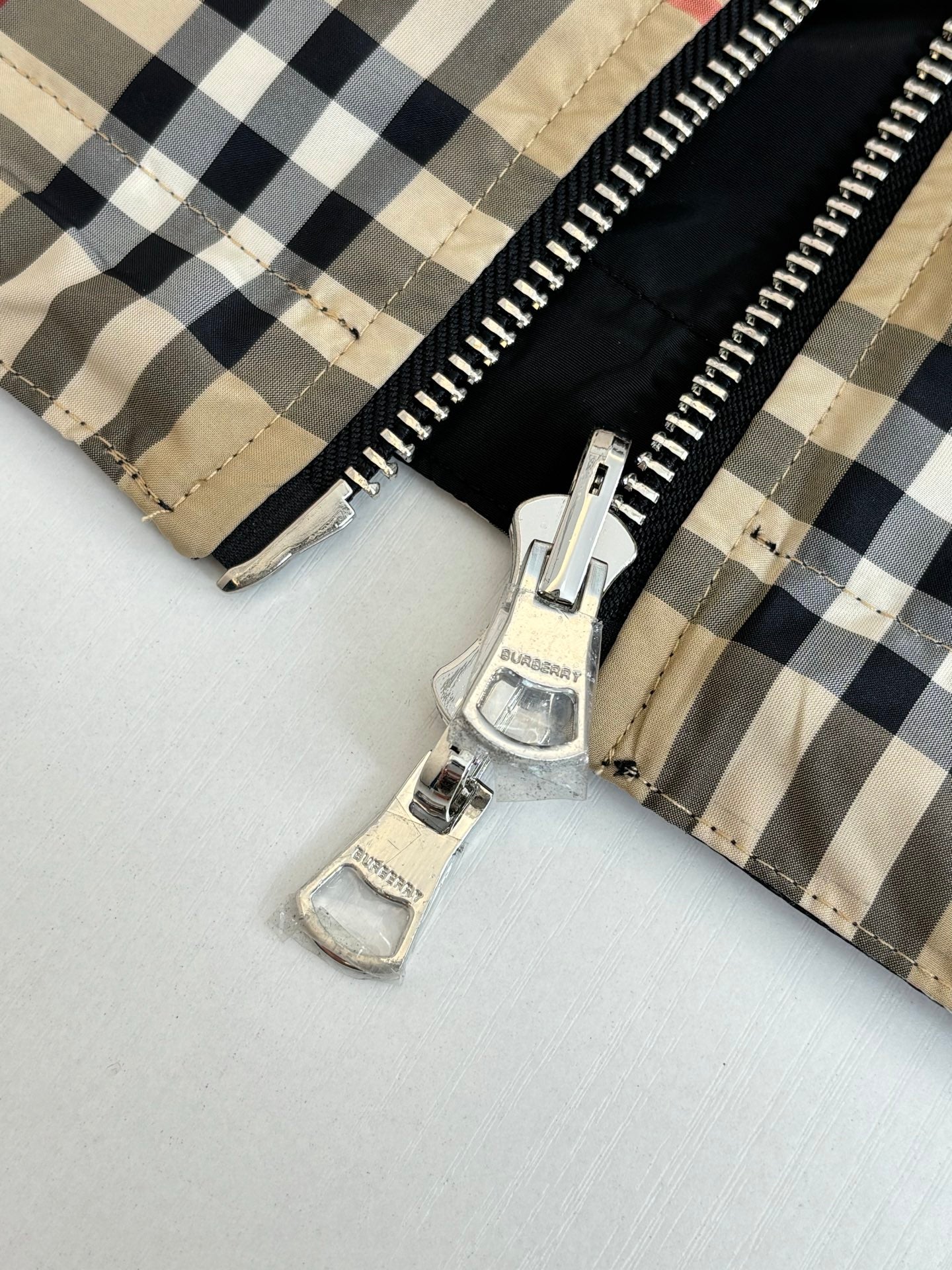 Plaid jacket with front zipper and snap strap details near hem