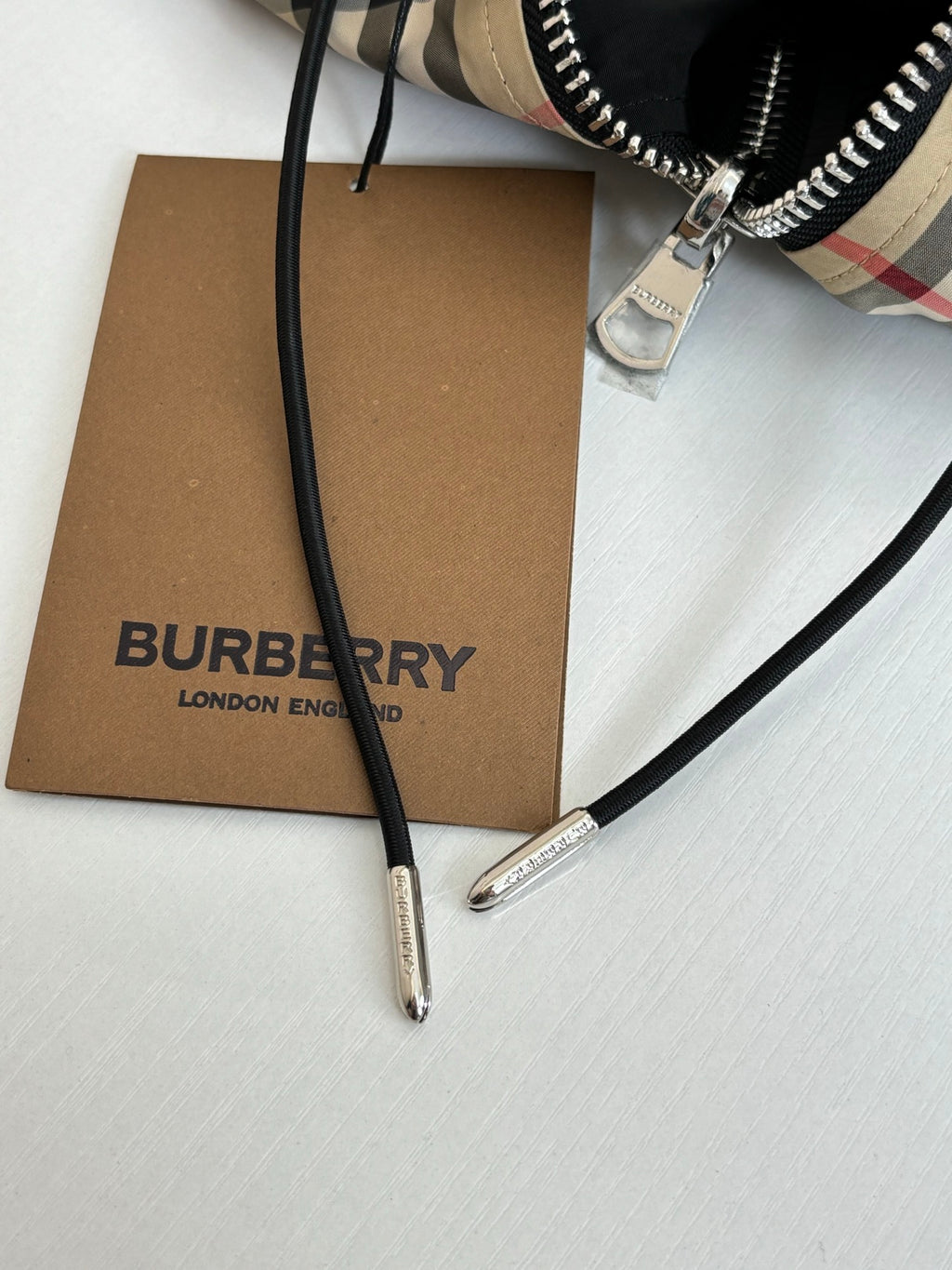 Black hood drawstring ends with metal aglets and Burberry clothing tag