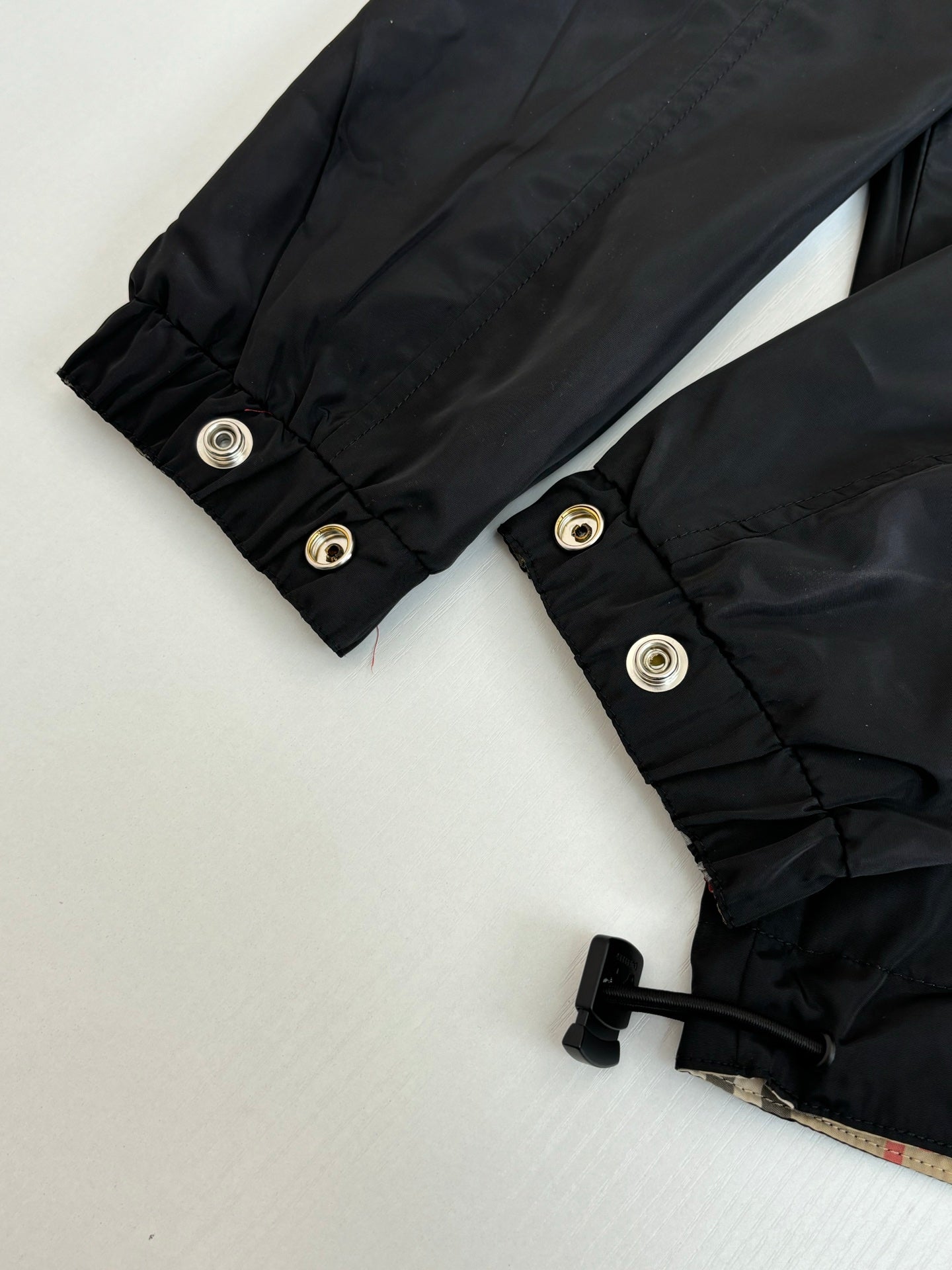 Black jacket cuffs with snap buttons and folded elastic hem