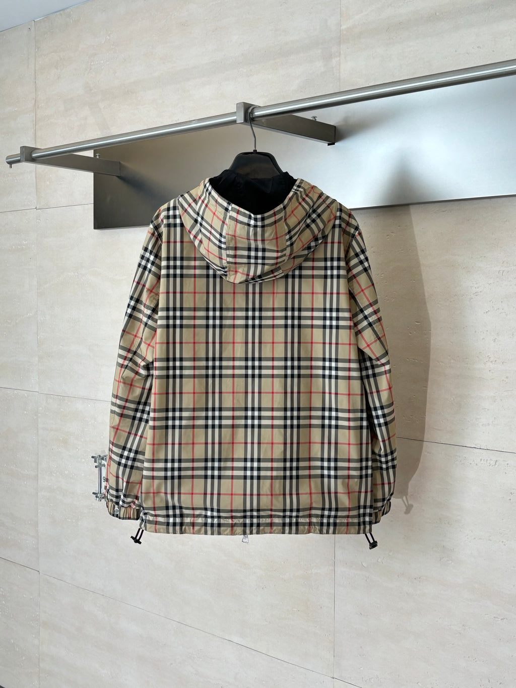 Plaid hooded jacket with black lining, front zipper, and drawcord hem