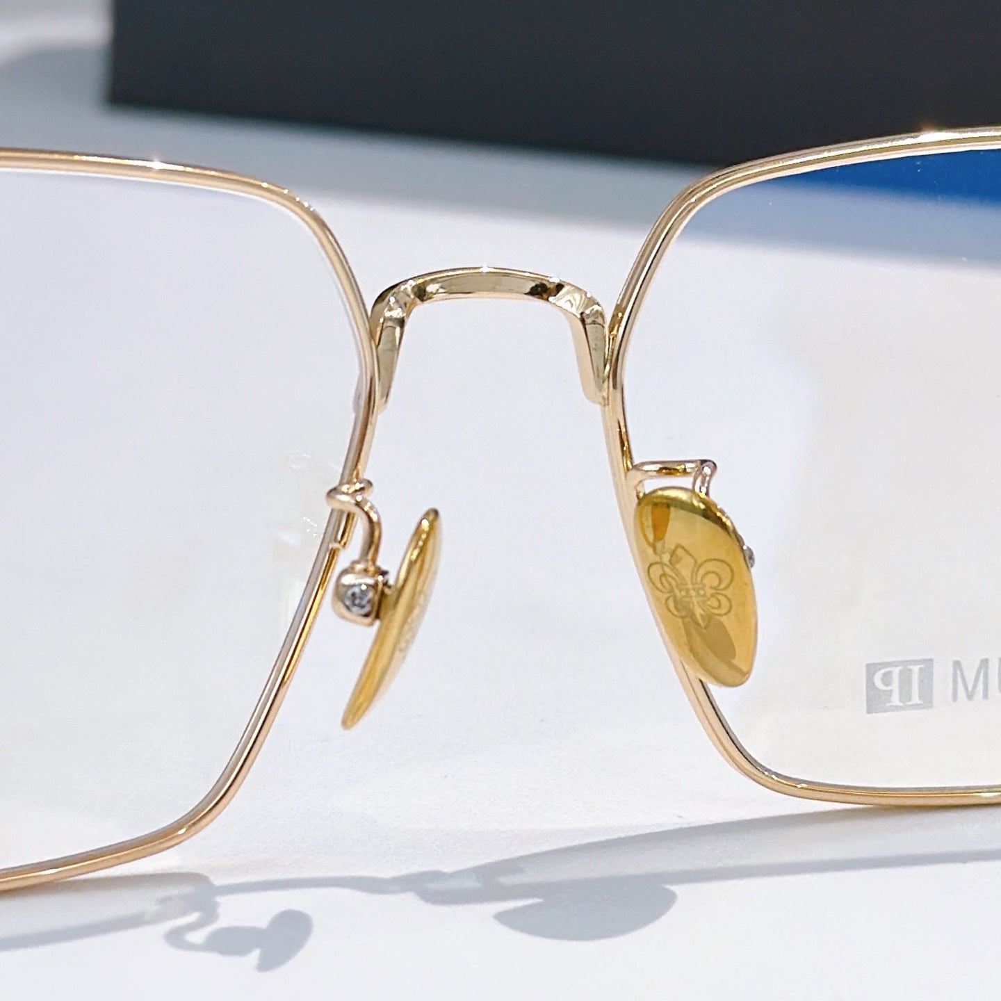 Gold rectangular eyeglasses close-up with blue lens insert and clear lenses