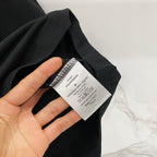 Black T-shirt fabric with care label tag held in hand