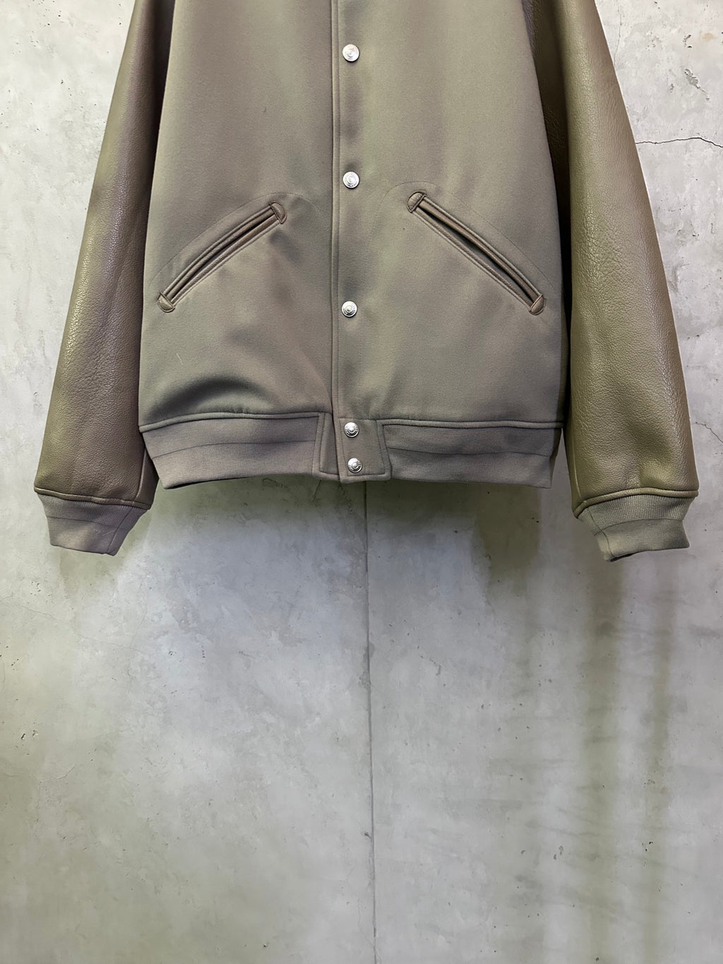 Olive jacket front with snap buttons and diagonal zip pockets