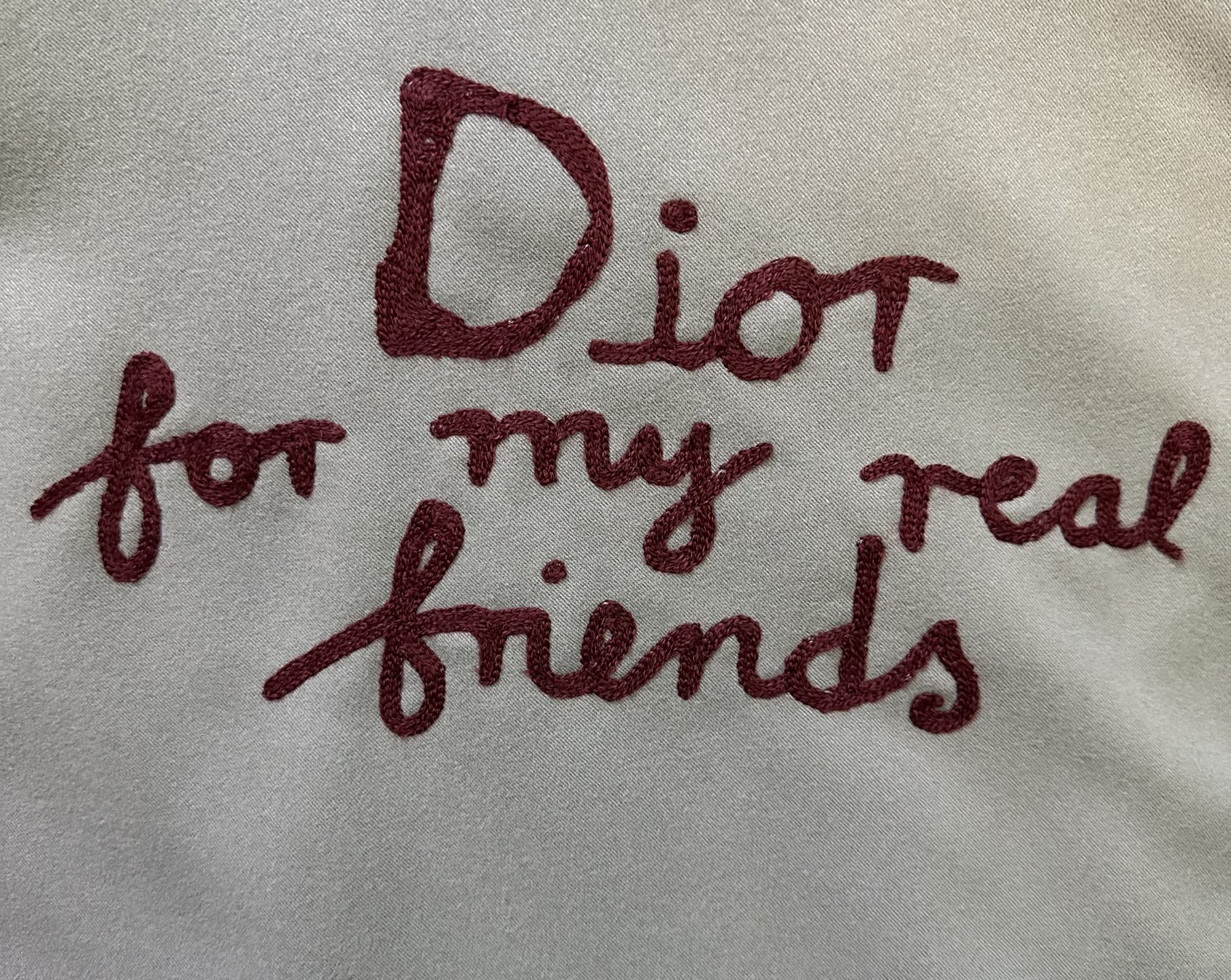 Burgundy embroidered text: “Dior for my real friends” on olive fabric
