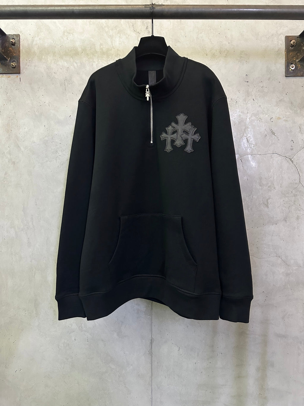 Black long-sleeve hoodie with half-zip, front pocket, and cross logo on chest.