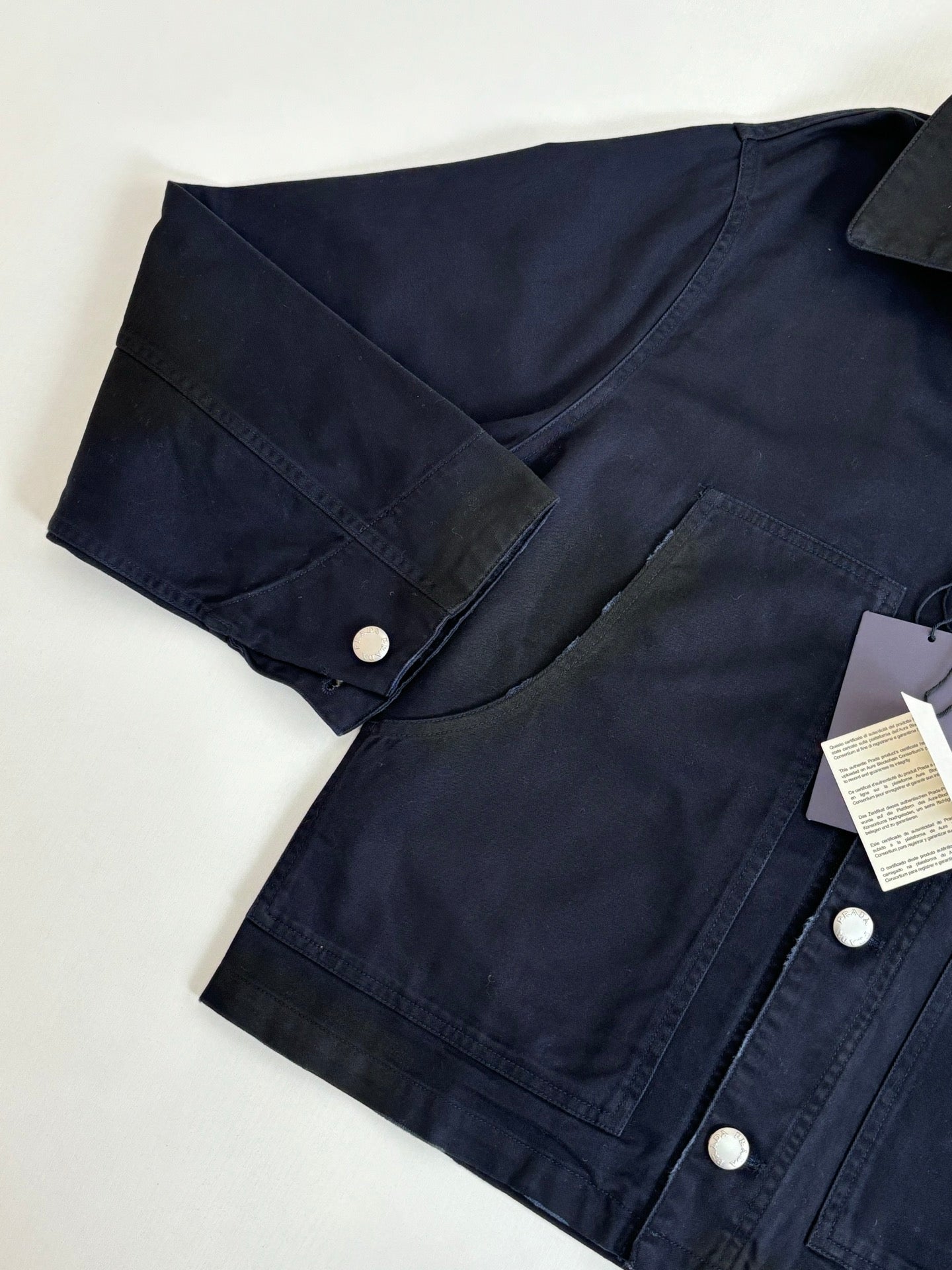 Prada long jacket close-up in dark navy, snap button placket and pocket seam
