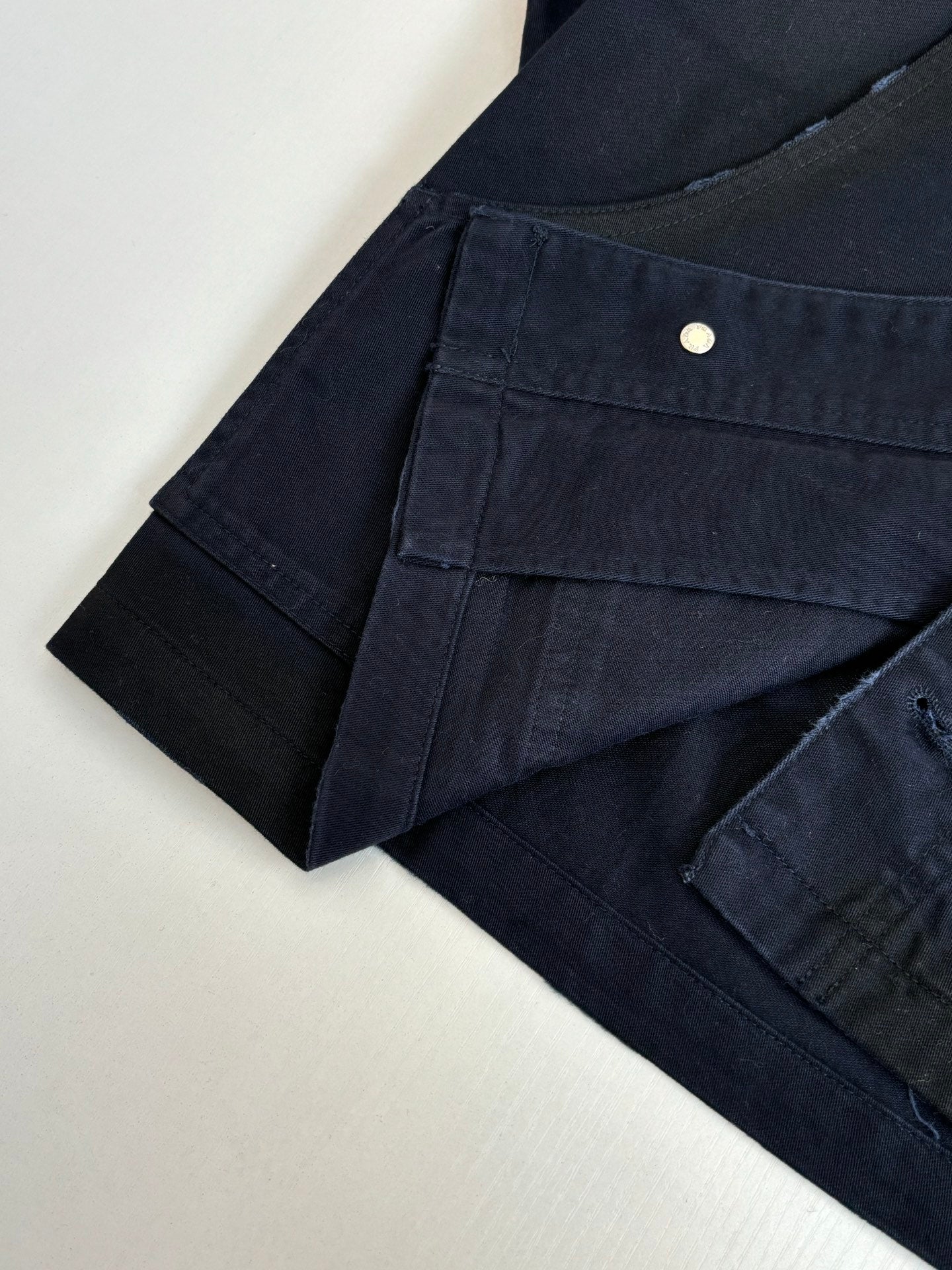 Navy long jacket front with buttoned pocket and curved seams