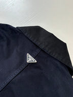Prada long jacket chest close-up with embroidered Prada logo patch on dark navy