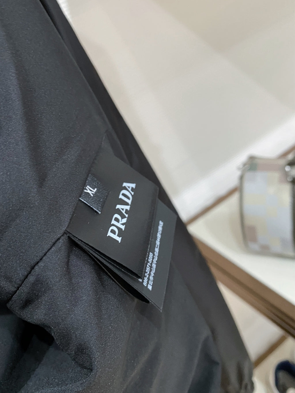 Prada brand label on black hooded jacket interior collar tag, close-up.