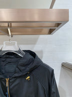 Black hooded jacket side view with front zip and gold zipper pull, cropped.