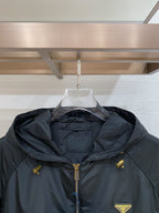 Black hooded jacket neckline detail with front zip, drawcords, and Prada logo patch.