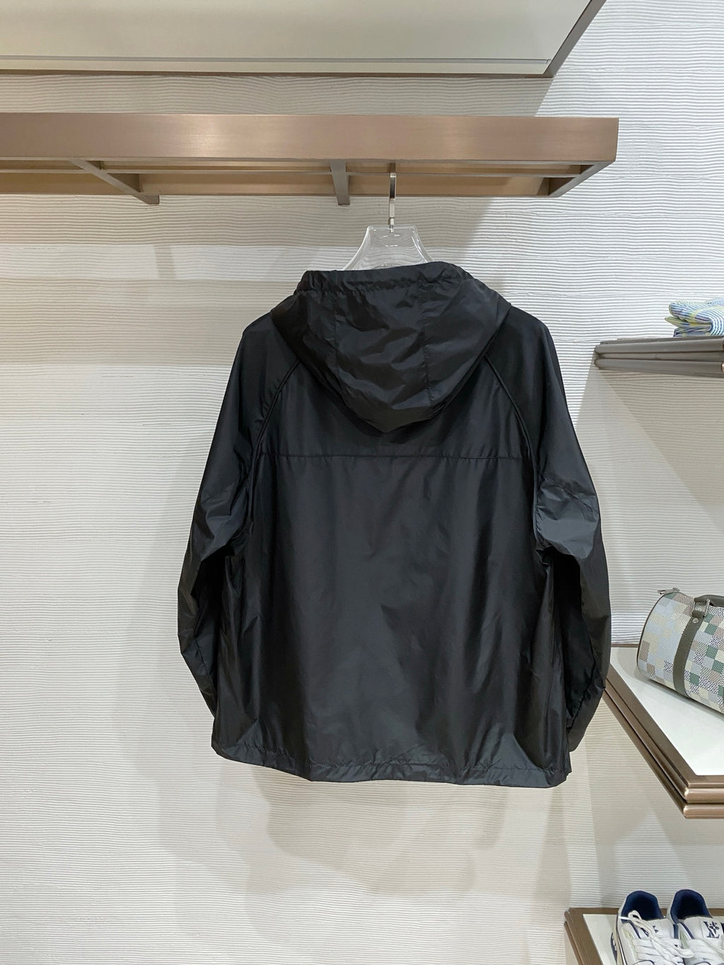 Black hooded jacket back view on hanger, full length with hood and sleeves.
