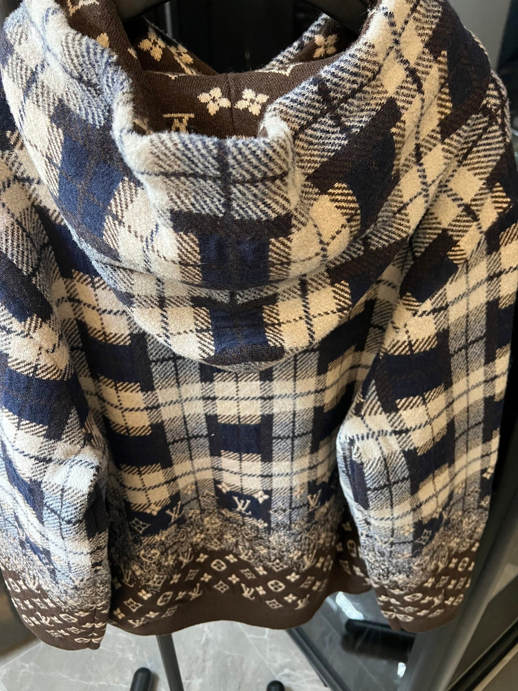 Hooded sweatshirt front close-up with plaid hood lining and brown monogram panel